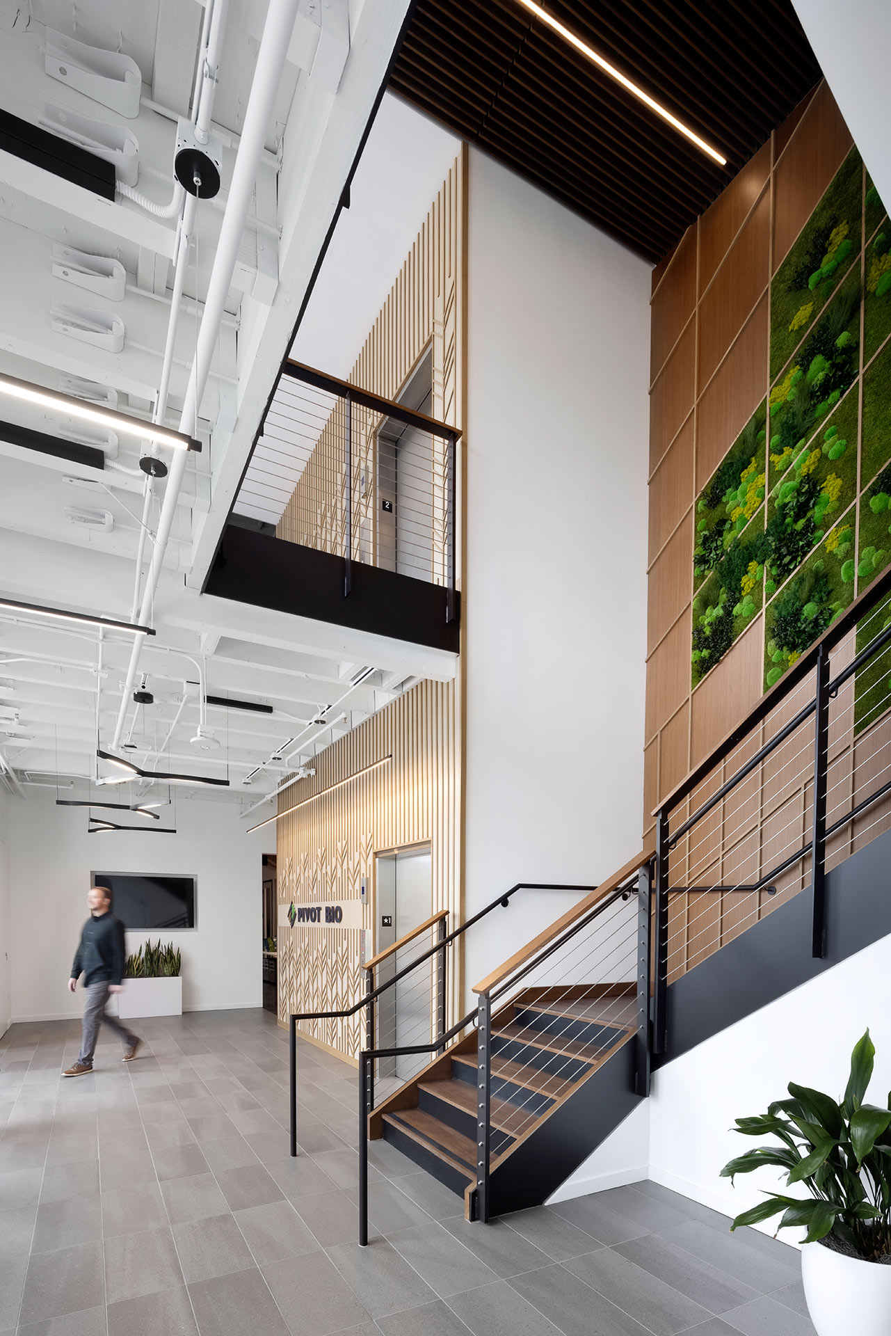 Interior at Pivot Bio life science facility, lobby and stairway with large geometric biophilia green wall and wood panels
