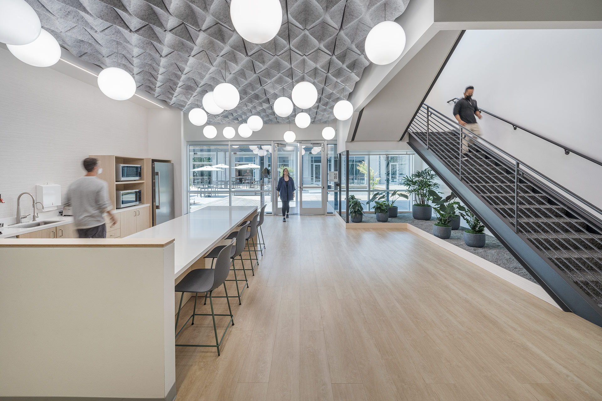 Interior at Takara Bio life science facility, breakroom kitchen and stairway with people moving through