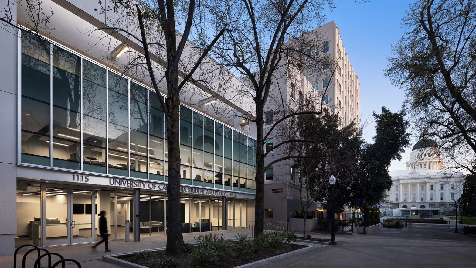 Exterior at UC Center Sacramento academic facility, evening view of the front of the building with UC signage and a view of the State Capitol building in the distance