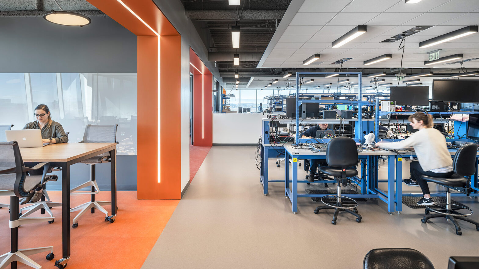 Interior at Verb Surgical HQ life science facility, lab with someone working and view of support collaboration space with someone using a laptop