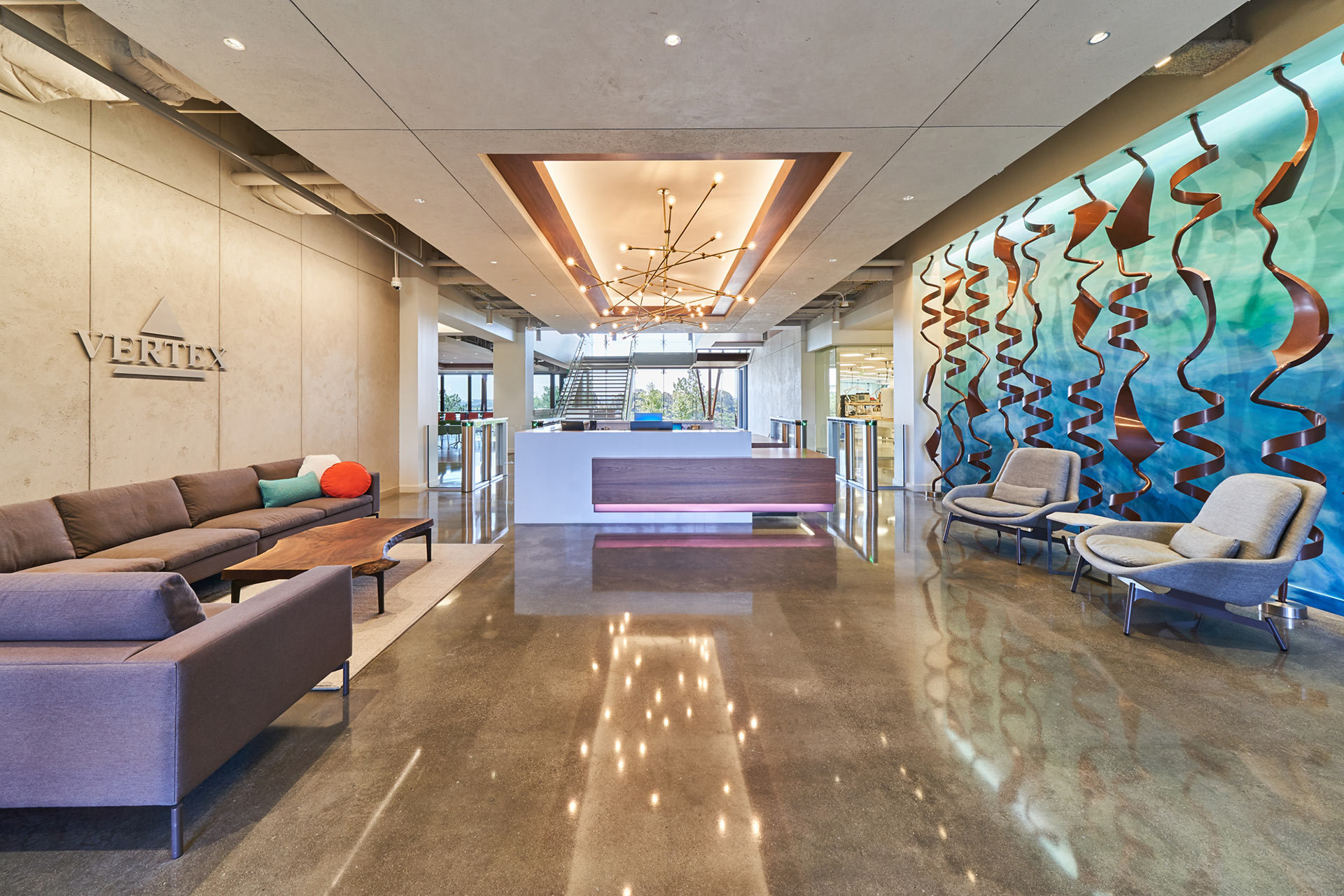 Interior at Vertex Pharmaceuticals life science facility, lobby and front desk with central stair in the background