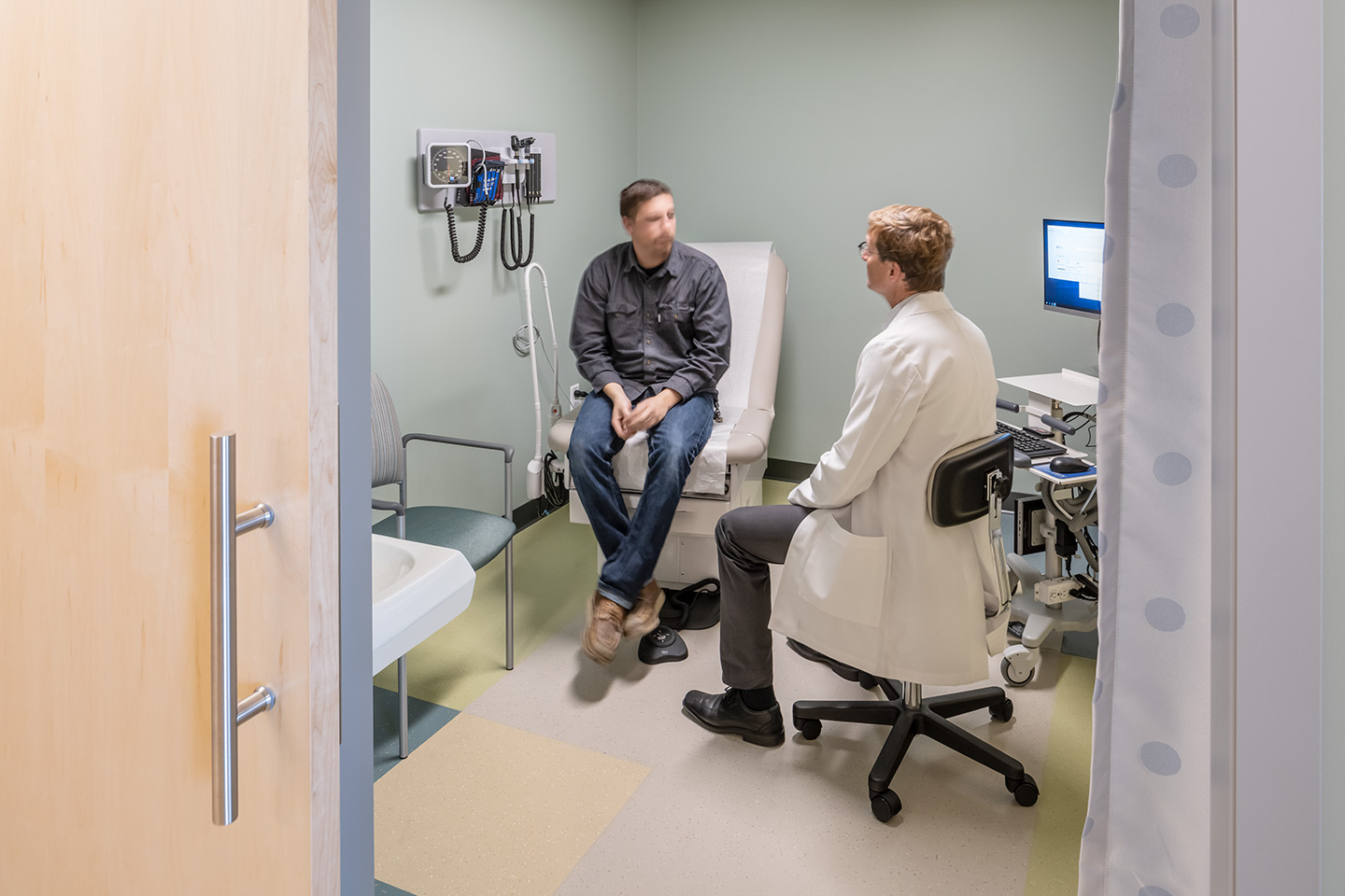 Interior of a healthcare medical office building doctor with patient in exam room